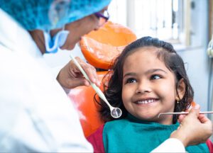 A girl smiling to a dentist during a dental exam.