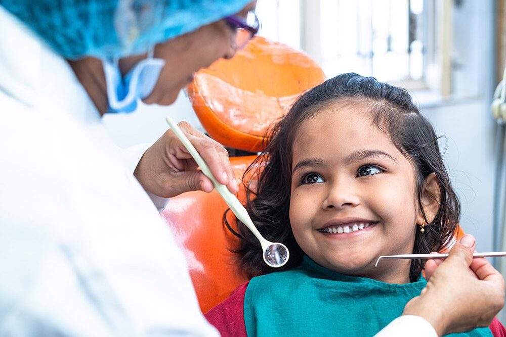A girl smiling to a dentist during a dental exam.